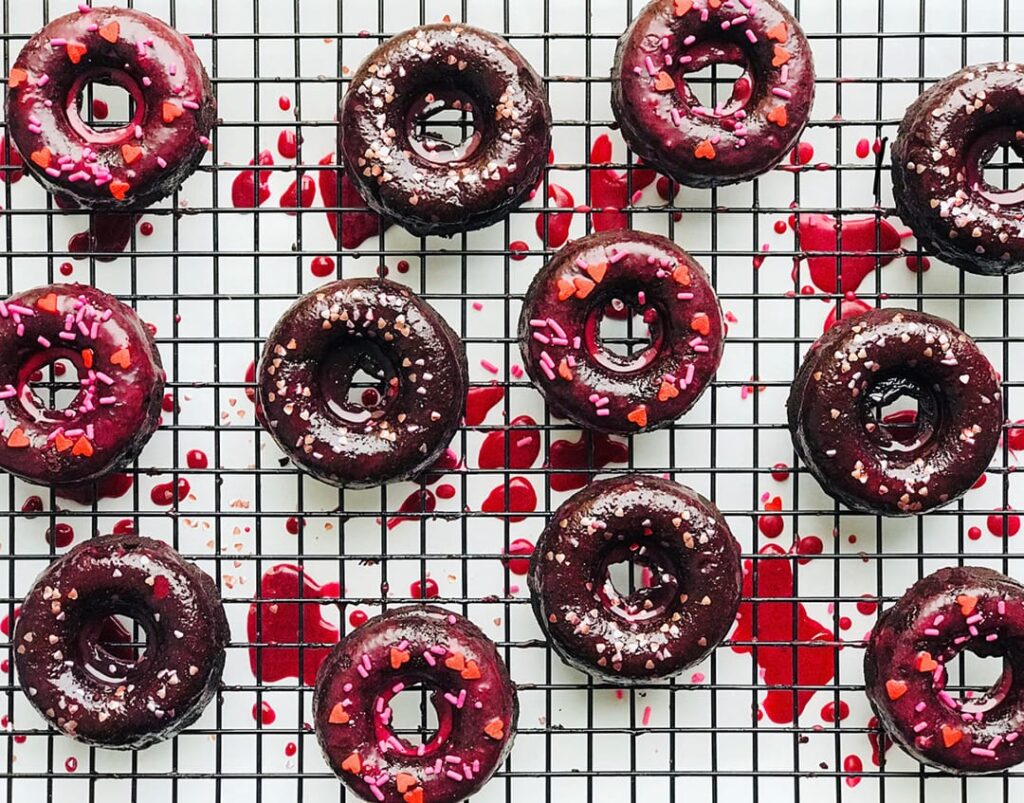Gluten-Free Red Velvet Donuts on tray with spatters of frosting