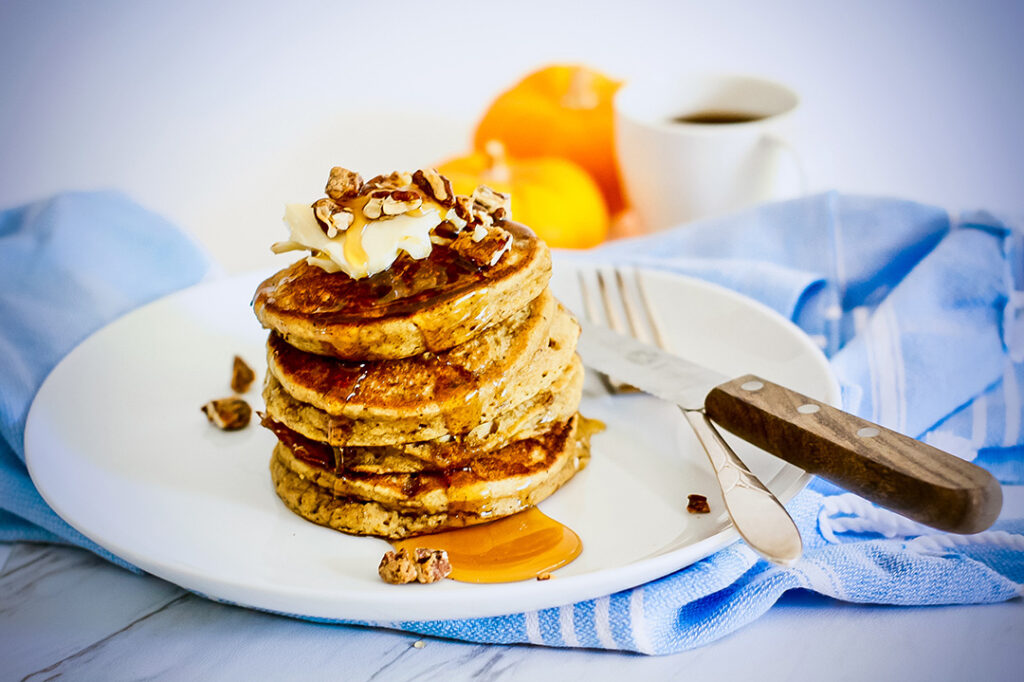 Gluten Free Pumpkin Pancakes Stacked on a plate with syrup drizzle