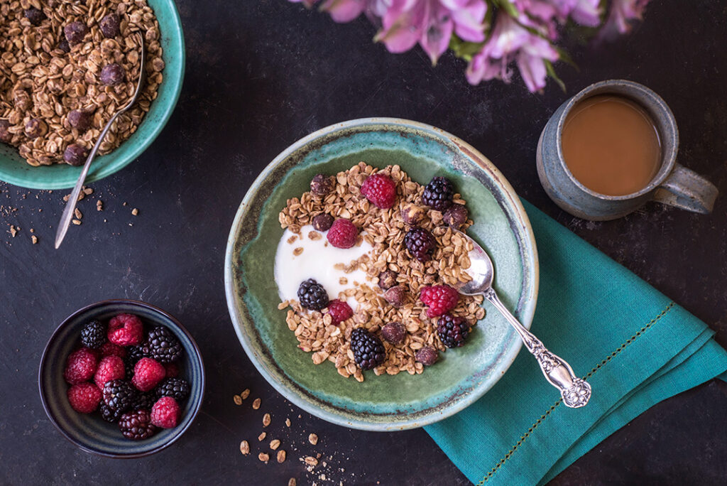 Vegan and Gluten-Free maple hazelnut granola in ceramic bowl, topped with fresh berries