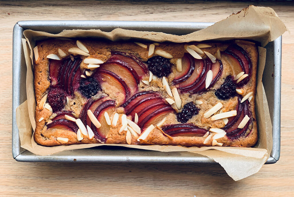 A gluten-free bread topped with seasonal fruit in pan
