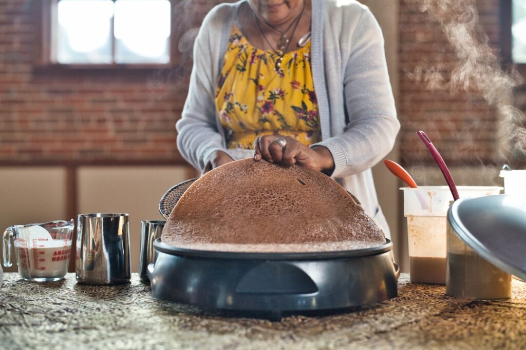 Making injera, woman lifting injera off pan