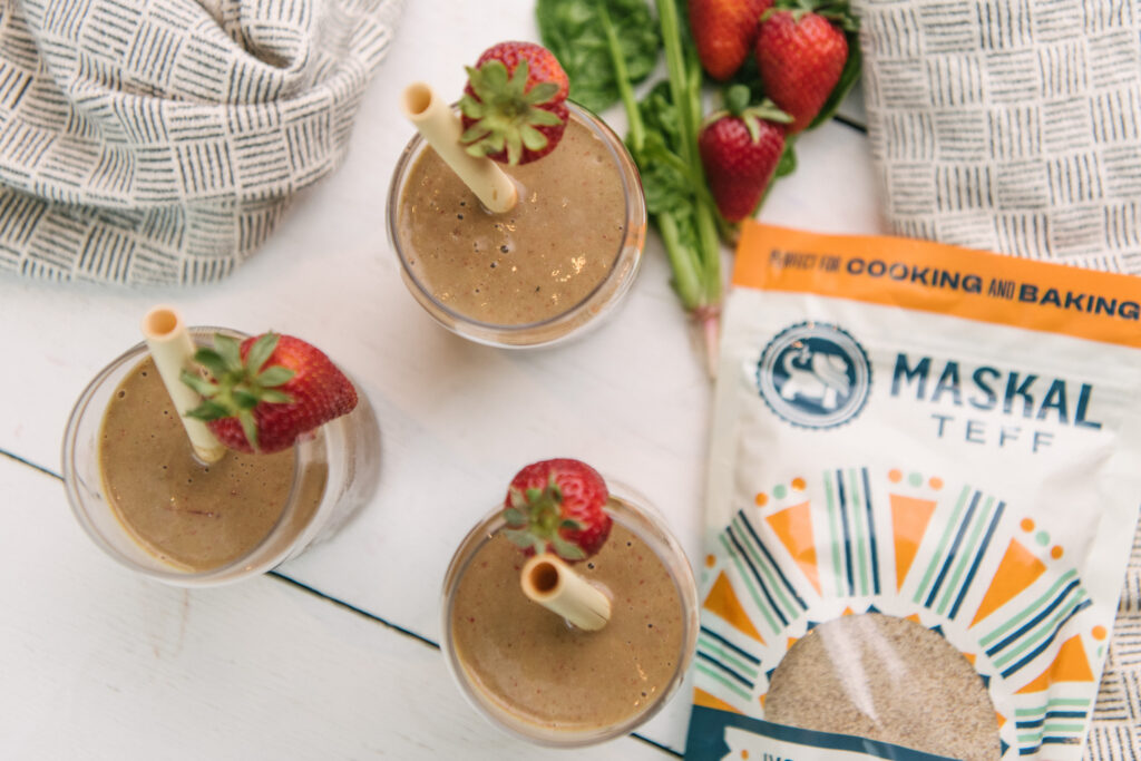 Teff & Greens Strawberry Smoothies in glasses with straws and strawberry garnishes