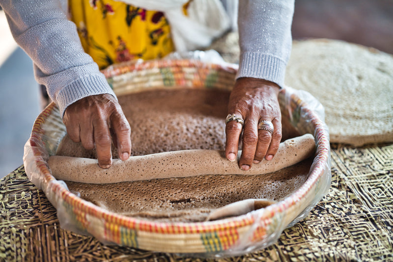 Woman rolling injera in a basket with a blurred background